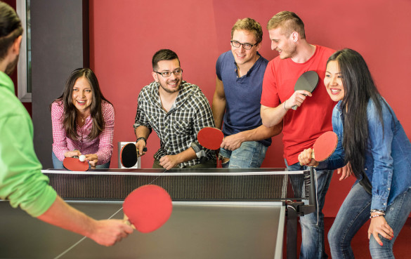 group-of-happy-young-friends-playing-ping-pong-table-tennis-shutterstock_270733406-2-1-585x369