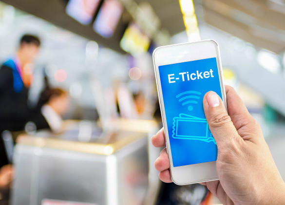 hand-holding-mobile-with-e-ticket-with-blur-airport-check-in-background-shutterstock_300059927-2-585x421