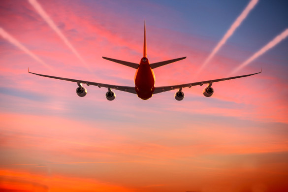 airplane-flying-in-the-sky-at-sunset-with-vapor-trails-istock_50476228_xlarge-2-585x390