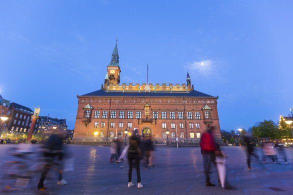 CIty hall in copenhagen, capital city of Denmark. Photo taken after sunset, during the blue hour. There are some blurred persons walking on the square. Travel and architecture themes.