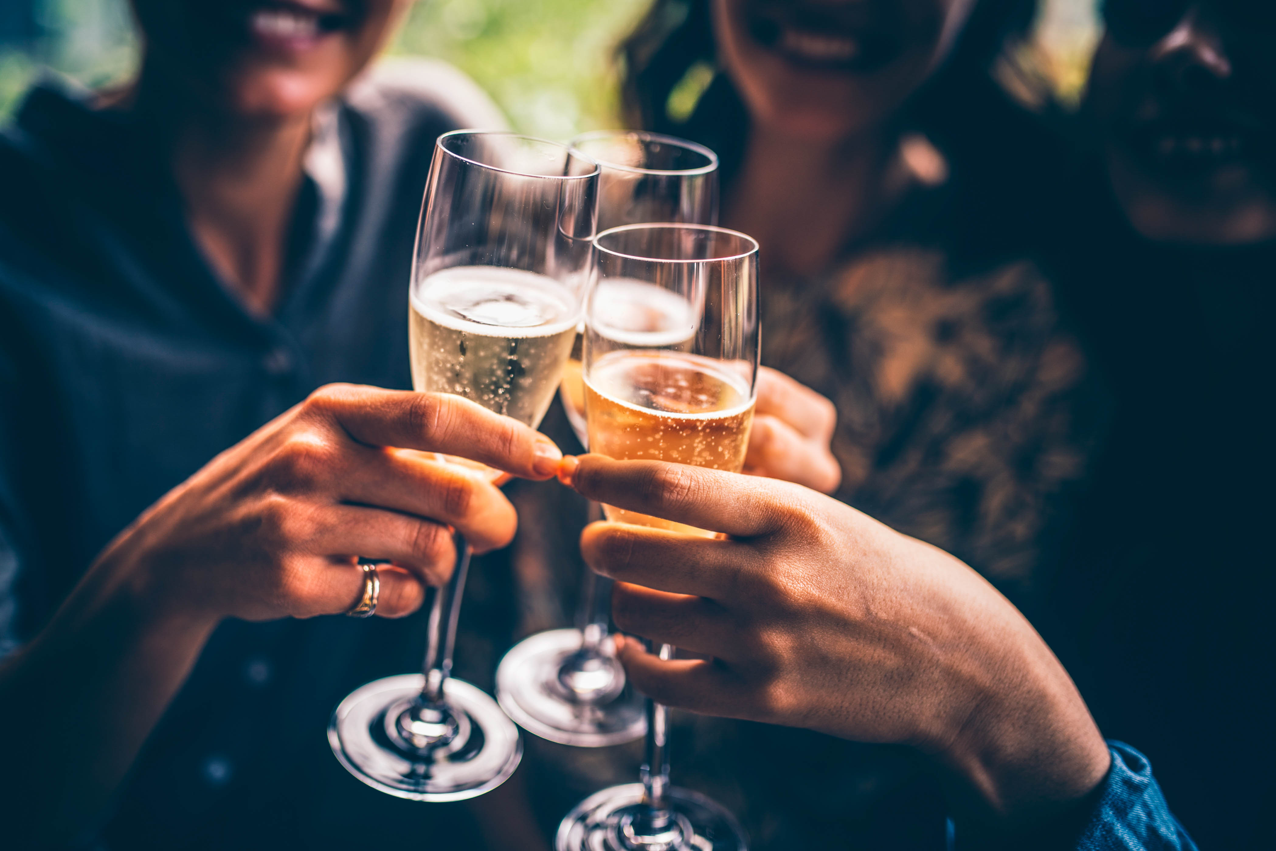 Three female friends celebrating with champagne. They are sitting in a bar and toasting with glasses of champagne.