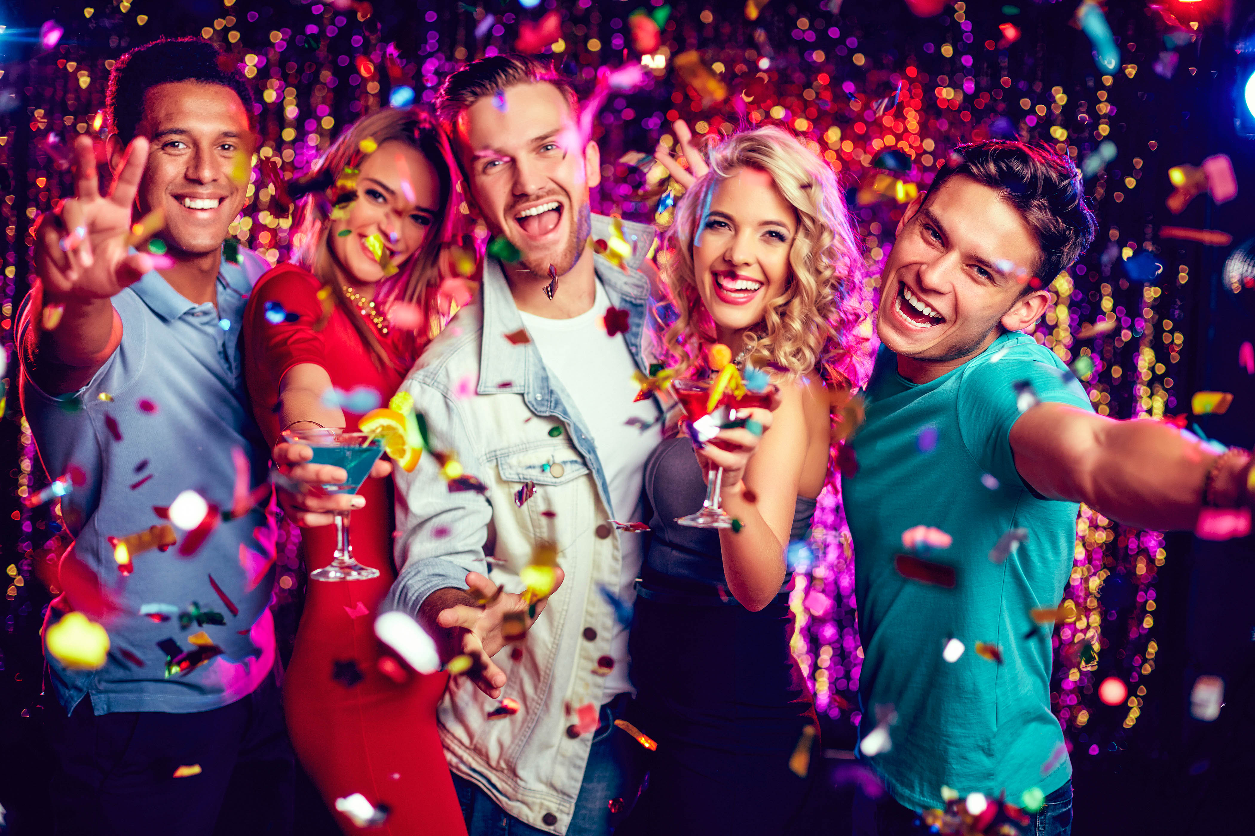 Group of ecstatic friends with cocktails looking at camera at party