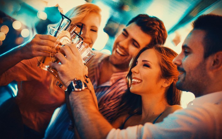 Group of young adult enjoying their night out in a club.Toasting with drinks,laughing and having casual conversation. Two couples on a double date.