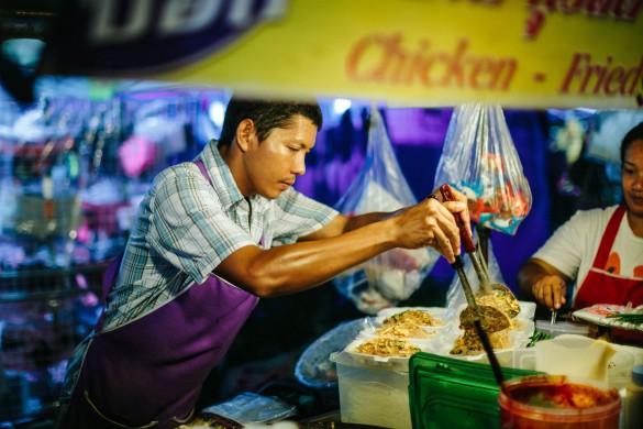 Patong, Thailand - February 15, 2013: Night food market in Thailand. Image was taken in Phuket, near the Banzaan market. Thai food vendor selling barbecue chicken. The area is popular with toursits and lively in the evenings especially with many street food vendors.