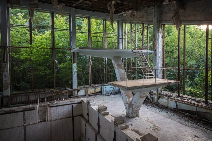 Abandoned-swimming-pool-in-Pripyat.-Destroyed-gym-in-a-radioactive-city.-The-street-is-overgrown-with-trees-and-bushes.-Jumping-tamplin-shutterstock_1383261332