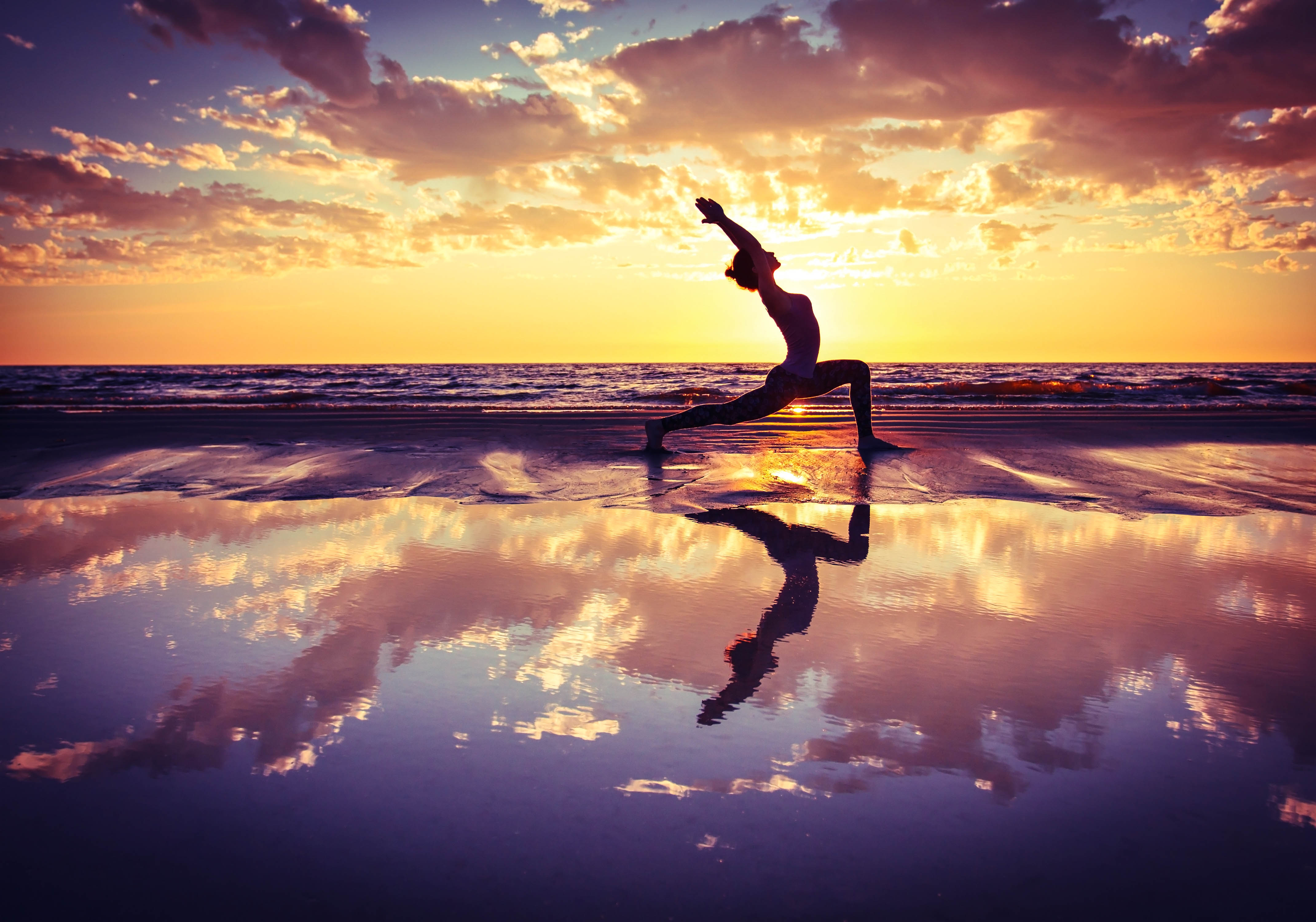 silhouette of woman practicing yoga on the beach at sunset shutterstock_304371815-2
