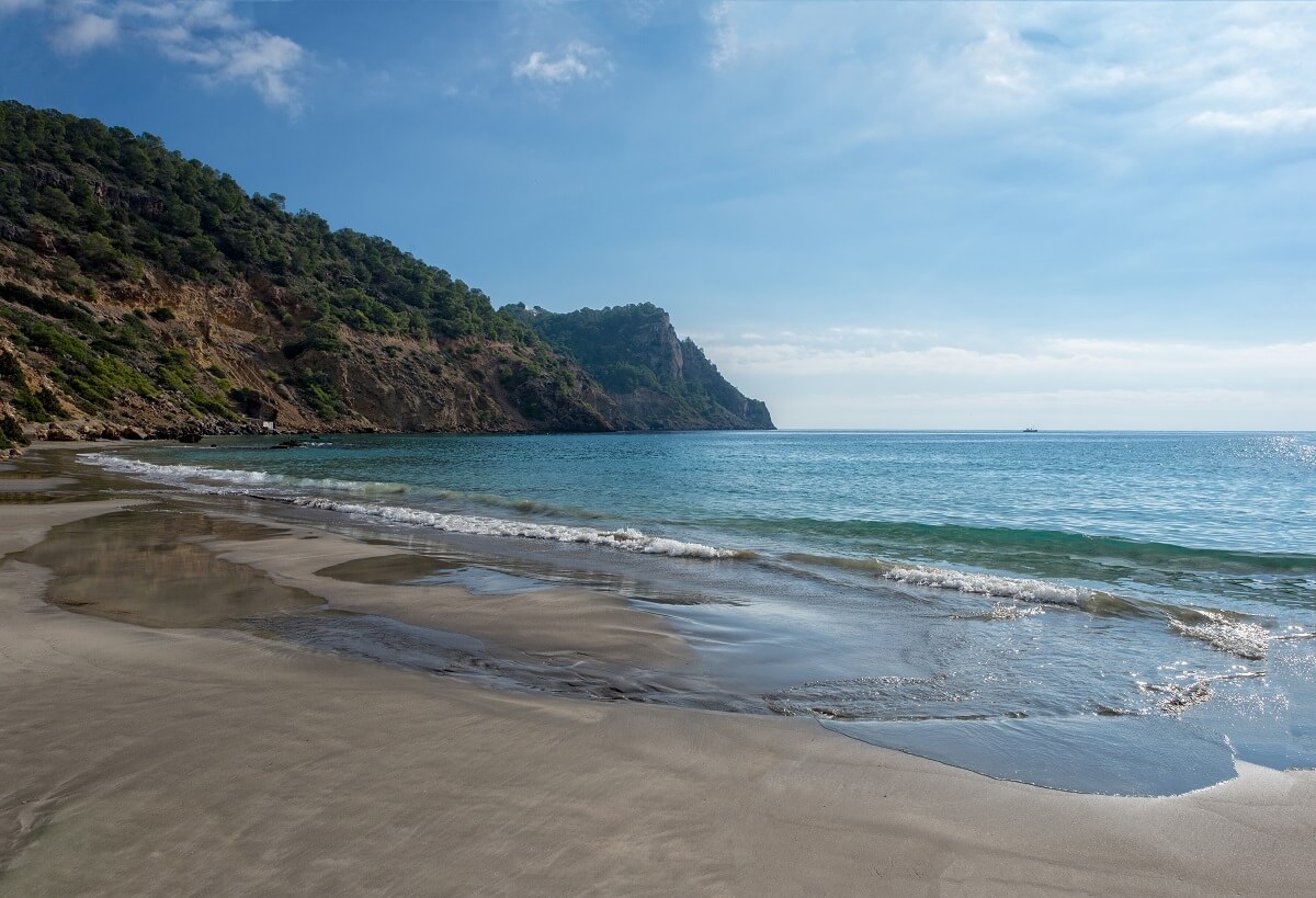 Der Strand Cala Boix auf Ibiza in Spanien besticht mit seinem dunklen Sand
