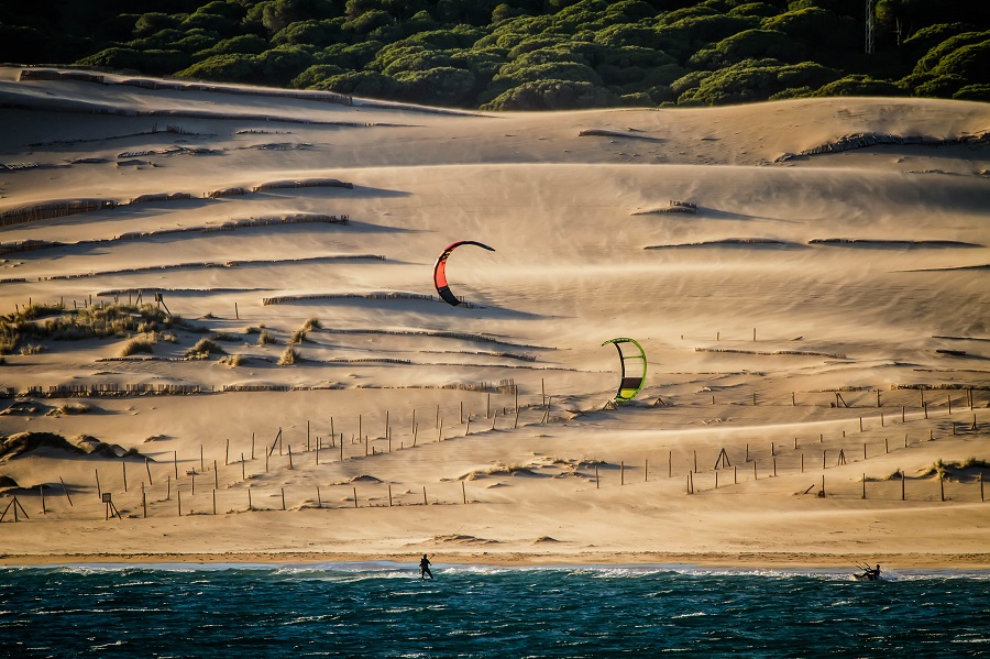 Andalusien, kiters are riding in front of sand dunes