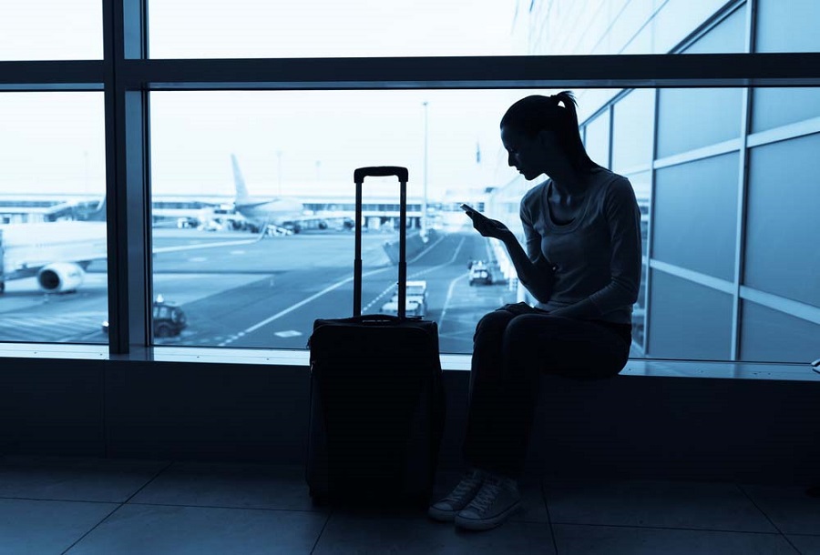 Frau sitzt am Flughafen und wartet auf ihren verspäteten Flug