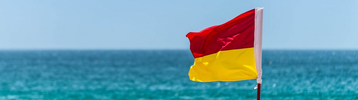 Red And Yellow Warning Sign Flag at the Beach