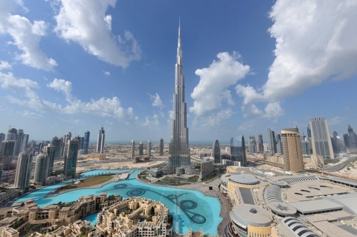 Himmelklarer Blick über Dubai mit dem dominanten Burj Khalifa im Zentrum, umgeben von Wolkenkratzern und der azurblauen Wasserfläche der Dubai Fountain.