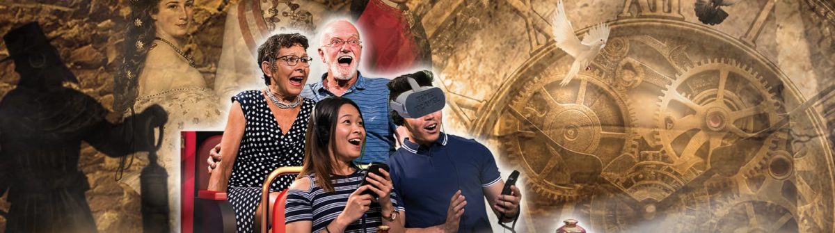 Vier lachende Personen, teils mit VR-Brillen, sitzen vor einer alten, steinernen Wand. Ein großes Uhrwerk ist rechts zu sehen, mit einem Schatten eines Ritters links. Eine Taube fliegt oben.