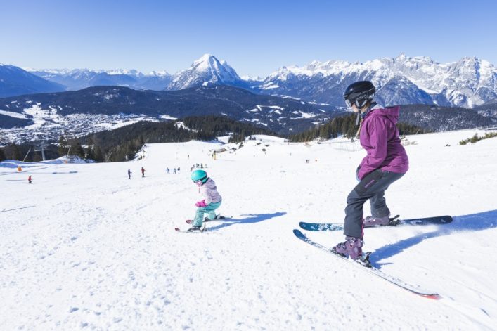 UG-TVB-Seefeld_Familien-Skifahren-in-der-Region-Seefeld-Mama-und-Tochter-auf-der-Piste-Blick-auf-Seefeld-Bergbahnen-Rosshuette-Seefeld